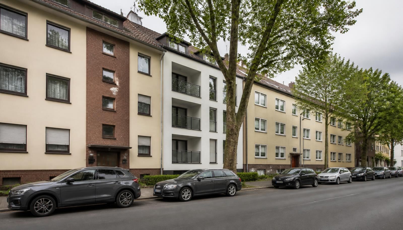 Mehrfamilienhäuser mit sanierten Fassaden in einer nordrhein-westfälischen Wohnstraße
