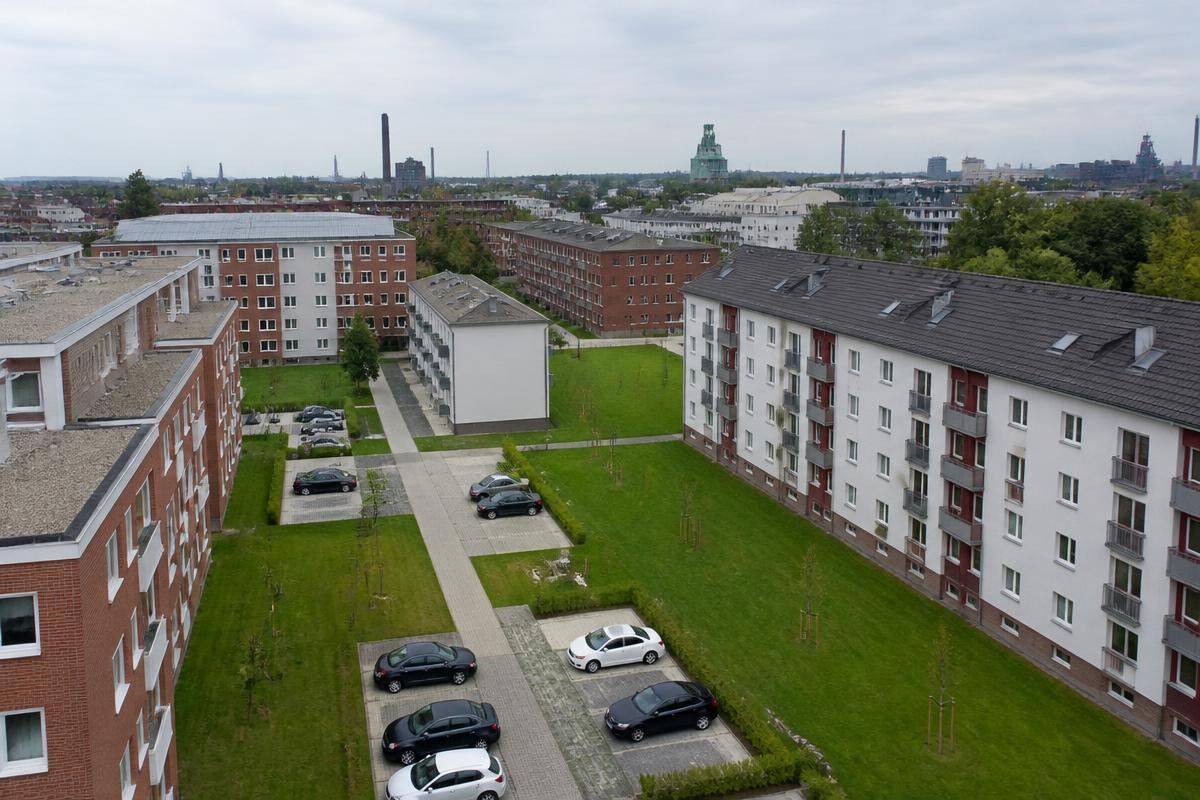 Sanierte Wohnblocks einer Siedlung im Ruhrgebiet mit Industriekulisse im Hintergrund